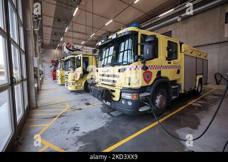 Un camion antincendio giallo nel garage di una stazione dei vigili del fuoco norvegese con altri tre camion dei vigili del fuoco fiancheggiati dietro Foto Stock