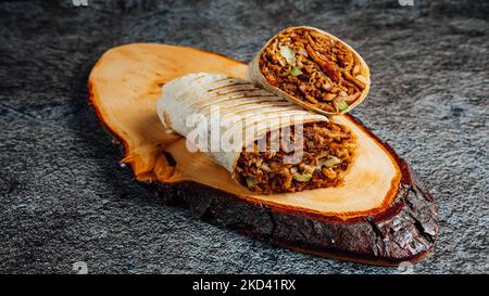 Un primo piano di burrito tagliato a metà su un pezzo di legno Foto Stock