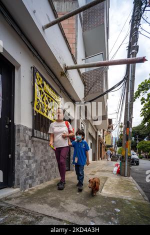Medellin, Antioquia, Colombia - Giugno 2 2022: Madre con Figlio con maschera viso Blu e Wiener-Dog a Leash cammina sul lato a piedi Foto Stock