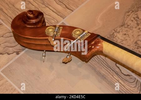 Il rotolo di un violoncello composto da nut pegbox e pioli closeup giacente su pavimento piastrellato - fuoco selettivo Foto Stock