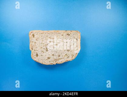 una singola fetta di pane fresco seminato isolato su uno sfondo blu scuro Foto Stock