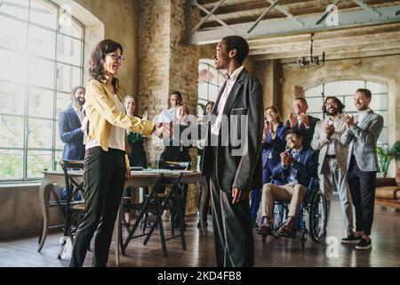 Donne d'affari multietniche che scuotono le mani davanti ai loro colleghi applaudendo in background - concetto di stile di vita aziendale Foto Stock