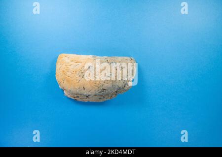 estremità crosta di una pagnotta con semi e muffa blu isolata su sfondo blu scuro Foto Stock