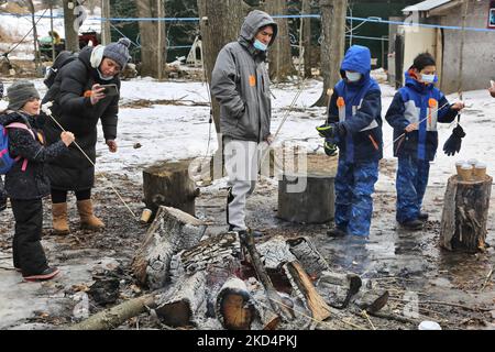 Persone che brinda marshmallows da un piccolo fuoco mentre visitano il sugarbush in una fattoria di sciroppo d'acero durante il Festival dello zucchero d'acero a Mount Albert, Ontario, Canada, il 05 marzo 2022. Il Festival dello zucchero d'acero celebra la produzione di sciroppo d'acero e i prodotti realizzati con sciroppo d'acero e partecipa a molte aziende agricole produttrici di sciroppo d'acero in Ontario e Quebec. Lo sciroppo d'acero è prodotto solo in Nord America. (Foto di Creative Touch Imaging Ltd./NurPhoto) Foto Stock