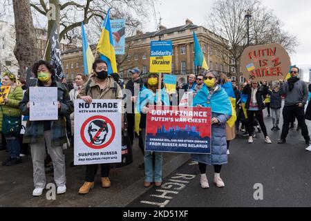 LONDRA, REGNO UNITO - 13 MARZO 2022: I dimostranti hanno cartelli che chiedono il divieto del commercio con la Russia mentre il popolo ucraino e i suoi sostenitori manifestano contro la guerra al di fuori di Downing Street il 18th° giorno dell'invasione militare russa in Ucraina il 13 marzo 2022 a Londra, Inghilterra. I dimostranti chiedono al governo britannico di sostenere l'Ucraina fornendo sistemi di difesa aerea e antimissili, chiudendo il cielo sull'Ucraina, attuando ulteriori sanzioni sugli oligarchi, nonché vietando il commercio di energia e fornendo aiuto e sostegno ai rifugiati, come si stima che più di 2,5 milioni di poliziotto Foto Stock