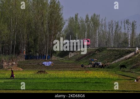 Una donna cammina mentre un treno ferroviario si sposta verso la sua destinazione alla periferia di Srinagar, Jammu e Kashmir, India il 28 marzo 2022. (Foto di Nasir Kachroo/NurPhoto) Foto Stock