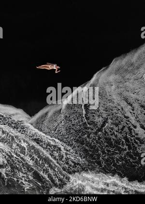 Una vista verticale aerea di una femmina in bicicletta galleggiante su acqua di mare schiumosa Foto Stock