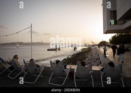 La gente assiste al tramonto sulla riva del fiume Tago a Lisbona, in Portogallo, il 29 marzo 2022. (Foto di Manuel Romano/NurPhoto) Foto Stock