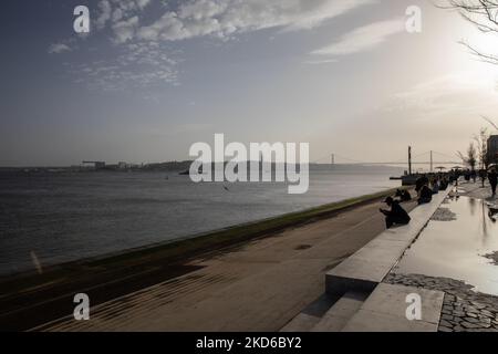 La gente assiste al tramonto sulla riva del fiume Tago a Lisbona, in Portogallo, il 29 marzo 2022. (Foto di Manuel Romano/NurPhoto) Foto Stock