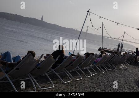 La gente assiste al tramonto sulla riva del fiume Tago a Lisbona, in Portogallo, il 29 marzo 2022. (Foto di Manuel Romano/NurPhoto) Foto Stock