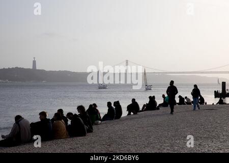 La gente assiste al tramonto sulla riva del fiume Tago a Lisbona, in Portogallo, il 29 marzo 2022. (Foto di Manuel Romano/NurPhoto) Foto Stock