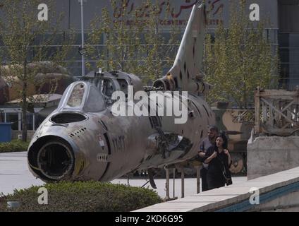 Un uomo iraniano e una donna passano davanti a un jet fighter iracheno schiantato fuori dal museo della Rivoluzione e della Santa difesa nel nord di Teheran durante il giorno di Sizdah Bedar, noto anche come Nature's Day, il 2 aprile 2022. Sizdah Bedar, noto anche come Nature's Day, è un festival iraniano che si tiene ogni anno il tredicesimo giorno di Farvardin (il primo mese del calendario iraniano), che le persone trascorrono del tempo all'aperto e segnano la fine delle vacanze a Nowruz in Iran. Il governo iraniano ha permesso alle persone di uscire dalle loro case e di frequentare luoghi all'aperto due anni dopo la nuova epidemia di coronavirus (COVID-19) in ira Foto Stock