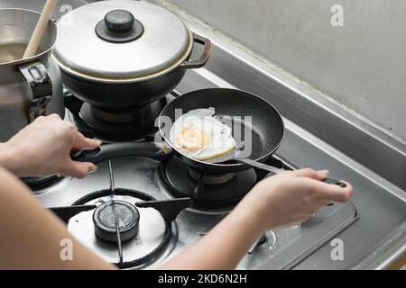 dettaglio di una donna che rimuove un uovo dalla padella con una spatola, preparando la tipica colazione colombiana Foto Stock