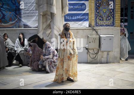 Una donna iraniana velata in un colorato chador (codice di abbigliamento islamico) con una maschera protettiva guarda mentre si trova in un santuario santo nel nord di Teheran il primo giorno del mese santo di Ramadan due anni dopo l'epidemia di COVID-19 in Iran, il 3 aprile 2022. (Foto di Morteza Nikoubazl/NurPhoto) Foto Stock