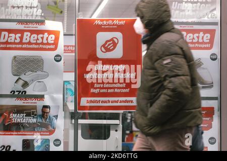 Il cartello "Please keept weiving face mask" si vede appeso di fronte a Media markt, il ristorante elettronico nel centro di Colonia, Germania il 4 aprile 2022 dopo che la Germania ha sollevato la maggior parte delle restrizioni del 19. (Foto di Ying Tang/NurPhoto) Foto Stock