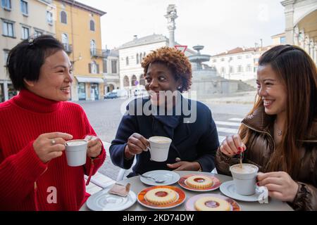 Amici multirazziali sorridenti e toothy che si guardano a vicenda gustando la loro colazione. Foto Stock