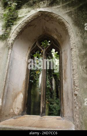 Finestra di St Dunstan nell'East Church Garden, chiostro medievale in pietra con muschio e viti che crescono intorno (City of London) Foto Stock