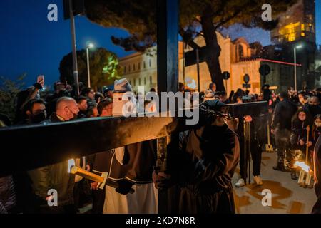 Il primo crocifisso in processione con una croce pesante sulle spalle a Noicattaro il 14 aprile 2022. A Noicattaro, la sera del Giovedì Santo, si svolge uno dei più antichi riti della settimana Santa in Puglia: La processione dei Crociferi. I crociferi sono uomini vestiti di abiti neri, cappe tirate giù sul volto e corona di spine sulla testa che, dalla chiesa della Madonna della lama, passeggia a piedi nudi per le strade del centro per visitare gli altari della riposizione allestita nelle chiese della città. Dopo che il falò è acceso, i crogioli si muovono in processione seguita da Tor Foto Stock