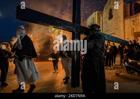 Il primo crocifisso in processione con una croce pesante sulle spalle a Noicattaro il 14 aprile 2022. A Noicattaro, la sera del Giovedì Santo, si svolge uno dei più antichi riti della settimana Santa in Puglia: La processione dei Crociferi. I crociferi sono uomini vestiti di abiti neri, cappe tirate giù sul volto e corona di spine sulla testa che, dalla chiesa della Madonna della lama, passeggia a piedi nudi per le strade del centro per visitare gli altari della riposizione allestita nelle chiese della città. Dopo che il falò è acceso, i crogioli si muovono in processione seguita da Tor Foto Stock