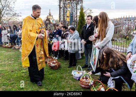 I fedeli ucraini partecipano alla tradizionale cerimonia di benedizione del sabato Santo nella chiesa greco-cattolica di Nadyby, Lviv Oblast, Ucraina, il 23 aprile 2022. Mentre quasi due mesi fa la Federazione russa invase l’Ucraina, il conflitto ha costretto più di 10 milioni di ucraini a fuggire dalle zone di guerra, sia all’interno che all’esterno. Lviv Oblast ospita molti dei rifugiati interni. Il villaggio di Nadyby e la sua chiesa greco-cattolica sono diventati un rifugio per decine di rifugiati da Kharkiv, Donesk e Zaporizhzhzhia Oblast. Mentre i fedeli ucraini si riuniscono per le celebrazioni pasquali ortodosse, i cristiani locali e la re Foto Stock