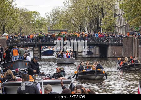 I Paesi Bassi festeggiano il King's Day dopo due anni di cancellazione a causa della pandemia di Coronavirus COVID-19 e delle restrizioni e misure di blocco. Migliaia di locali e visitatori hanno visitato i canali di Amsterdam per celebrare con varie feste il compleanno di Re Willem-Alexander conosciuto come Koningsdag, una festa nazionale olandese. Tutti i tipi di barche e navi sono visti nei canali che passano sotto i famosi ponti e vicino alle case strette di Amsterdam con persone che ballano e divertirsi. Le barche sfilano nei canali interni della città mentre i viaggiatori si riuniscono per le strade. Du Foto Stock