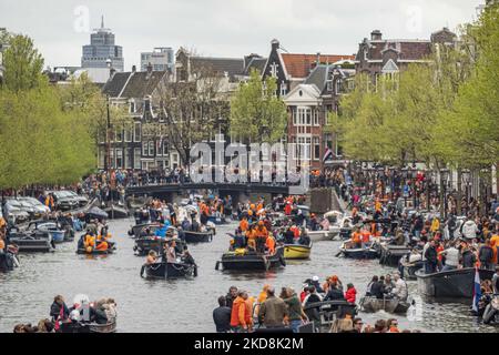 I Paesi Bassi festeggiano il King's Day dopo due anni di cancellazione a causa della pandemia di Coronavirus COVID-19 e delle restrizioni e misure di blocco. Migliaia di locali e visitatori hanno visitato i canali di Amsterdam per celebrare con varie feste il compleanno di Re Willem-Alexander conosciuto come Koningsdag, una festa nazionale olandese. Tutti i tipi di barche e navi sono visti nei canali che passano sotto i famosi ponti e vicino alle case strette di Amsterdam con persone che ballano e divertirsi. Le barche sfilano nei canali interni della città mentre i viaggiatori si riuniscono per le strade. Du Foto Stock