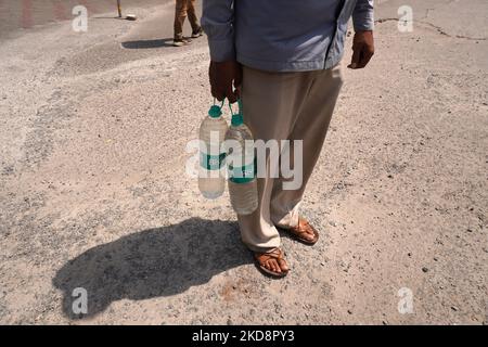 Un uomo cammina con le bottiglie d'acqua riempite ad una stazione di benzina, in una calda giornata estiva a Nuova Delhi, India il 30 aprile 2022. (Foto di Mayank Makhija/NurPhoto) Foto Stock