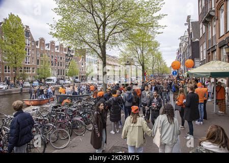 I Paesi Bassi festeggiano il King's Day dopo due anni di cancellazione a causa della pandemia di Coronavirus COVID-19 e delle restrizioni e misure di blocco. Migliaia di abitanti del luogo, festeggiatori e visitatori hanno visitato il centro della città, i parchi vicino al Rijksmuseum, i canali di Amsterdam per celebrare con varie feste il compleanno del re Willem-Alexander conosciuto come Koningsdag, una festa nazionale olandese. Tutti i tipi di barche e navi sono visti nei canali che passano sotto i famosi ponti e vicino alle case strette di Amsterdam con persone che ballano e divertirsi. Le barche sfilano giù nel dentro Foto Stock