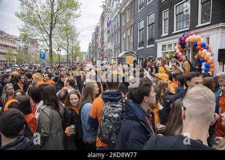 Le persone ballano, festeggiano e si divertono dopo aver bevuto alcolici di fronte ai bar e ai canali. Folle di persone che indossano principalmente abiti arancioni e che hanno la bandiera olandese come si vede nelle strade di Amsterdam, mentre i Paesi Bassi celebra il giorno del Re dopo due anni di cancellazione a causa della pandemia di Coronavirus COVID-19 e le restrizioni e misure di blocco. Migliaia di abitanti del luogo, festeggiatori e visitatori hanno visitato il centro della città, i parchi vicino al Rijksmuseum, i canali di Amsterdam per celebrare con vari festeggiamenti il compleanno del re Willem-Alexander conosciuto come Koningsdag, un olandese n Foto Stock