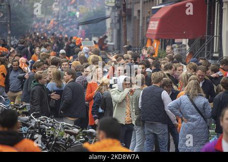 Folle di persone che indossano principalmente abiti arancioni e che hanno la bandiera olandese come si vede nelle strade di Amsterdam, mentre i Paesi Bassi celebra il giorno del Re dopo due anni di cancellazione a causa della pandemia di Coronavirus COVID-19 e le restrizioni e misure di blocco. Migliaia di abitanti del luogo, festeggiatori e visitatori hanno visitato il centro della città, i parchi vicino al Rijksmuseum, i canali di Amsterdam per celebrare con varie feste il compleanno del re Willem-Alexander conosciuto come Koningsdag, una festa nazionale olandese. Tutti i tipi di barche e imbarcazioni sono visibili nei canali che passano sotto i famosi ponti Foto Stock