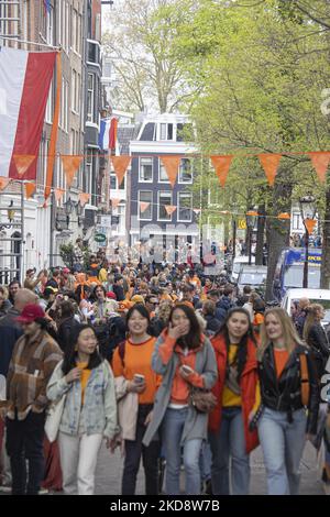 Folle di persone che indossano principalmente abiti arancioni e che hanno la bandiera olandese come si vede nelle strade di Amsterdam, mentre i Paesi Bassi celebra il giorno del Re dopo due anni di cancellazione a causa della pandemia di Coronavirus COVID-19 e le restrizioni e misure di blocco. Migliaia di abitanti del luogo, festeggiatori e visitatori hanno visitato il centro della città, i parchi vicino al Rijksmuseum, i canali di Amsterdam per celebrare con varie feste il compleanno del re Willem-Alexander conosciuto come Koningsdag, una festa nazionale olandese. Tutti i tipi di barche e imbarcazioni sono visibili nei canali che passano sotto i famosi ponti Foto Stock