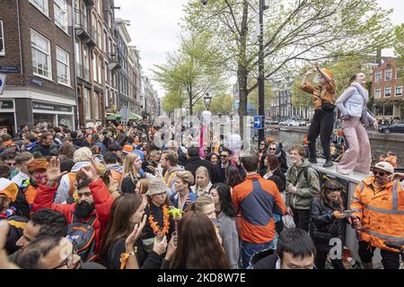 Le persone ballano, festeggiano e si divertono dopo aver bevuto alcolici di fronte ai bar e ai canali. Folle di persone che indossano principalmente abiti arancioni e che hanno la bandiera olandese come si vede nelle strade di Amsterdam, mentre i Paesi Bassi celebra il giorno del Re dopo due anni di cancellazione a causa della pandemia di Coronavirus COVID-19 e le restrizioni e misure di blocco. Migliaia di abitanti del luogo, festeggiatori e visitatori hanno visitato il centro della città, i parchi vicino al Rijksmuseum, i canali di Amsterdam per celebrare con vari festeggiamenti il compleanno del re Willem-Alexander conosciuto come Koningsdag, un olandese n Foto Stock