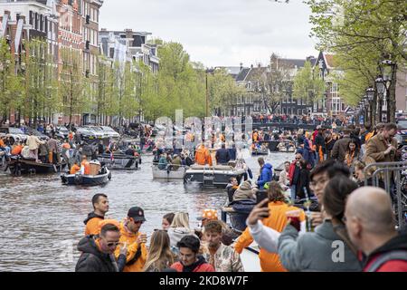 Le persone ballano, festeggiano e si divertono dopo aver bevuto alcolici di fronte ai bar e ai canali. Folle di persone che indossano principalmente abiti arancioni e che hanno la bandiera olandese come si vede nelle strade di Amsterdam, mentre i Paesi Bassi celebra il giorno del Re dopo due anni di cancellazione a causa della pandemia di Coronavirus COVID-19 e le restrizioni e misure di blocco. Migliaia di abitanti del luogo, festeggiatori e visitatori hanno visitato il centro della città, i parchi vicino al Rijksmuseum, i canali di Amsterdam per celebrare con vari festeggiamenti il compleanno del re Willem-Alexander conosciuto come Koningsdag, un olandese n Foto Stock