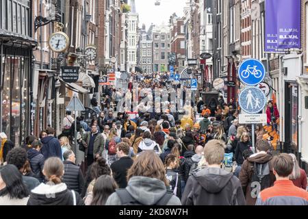 Folle di persone che indossano principalmente abiti arancioni e che hanno la bandiera olandese come si vede nelle strade di Amsterdam, mentre i Paesi Bassi celebra il giorno del Re dopo due anni di cancellazione a causa della pandemia di Coronavirus COVID-19 e le restrizioni e misure di blocco. Migliaia di abitanti del luogo, festeggiatori e visitatori hanno visitato il centro della città, i parchi vicino al Rijksmuseum, i canali di Amsterdam per celebrare con varie feste il compleanno del re Willem-Alexander conosciuto come Koningsdag, una festa nazionale olandese. Tutti i tipi di barche e imbarcazioni sono visibili nei canali che passano sotto i famosi ponti Foto Stock