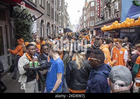 Folle di persone che indossano principalmente abiti arancioni e che hanno la bandiera olandese come si vede nelle strade di Amsterdam, mentre i Paesi Bassi celebra il giorno del Re dopo due anni di cancellazione a causa della pandemia di Coronavirus COVID-19 e le restrizioni e misure di blocco. Migliaia di abitanti del luogo, festeggiatori e visitatori hanno visitato il centro della città, i parchi vicino al Rijksmuseum, i canali di Amsterdam per celebrare con varie feste il compleanno del re Willem-Alexander conosciuto come Koningsdag, una festa nazionale olandese. Tutti i tipi di barche e imbarcazioni sono visibili nei canali che passano sotto i famosi ponti Foto Stock