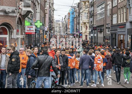 Folle di persone che indossano principalmente abiti arancioni e che hanno la bandiera olandese come si vede nelle strade di Amsterdam, mentre i Paesi Bassi celebra il giorno del Re dopo due anni di cancellazione a causa della pandemia di Coronavirus COVID-19 e le restrizioni e misure di blocco. Migliaia di abitanti del luogo, festeggiatori e visitatori hanno visitato il centro della città, i parchi vicino al Rijksmuseum, i canali di Amsterdam per celebrare con varie feste il compleanno del re Willem-Alexander conosciuto come Koningsdag, una festa nazionale olandese. Tutti i tipi di barche e imbarcazioni sono visibili nei canali che passano sotto i famosi ponti Foto Stock