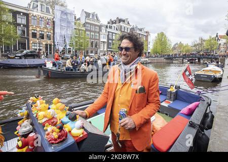 I Paesi Bassi festeggiano il King's Day dopo due anni di cancellazione a causa della pandemia di Coronavirus COVID-19 e delle restrizioni e misure di blocco. Migliaia di abitanti del luogo, festeggiatori e visitatori hanno visitato il centro della città, i parchi vicino al Rijksmuseum, i canali di Amsterdam per celebrare con varie feste il compleanno del re Willem-Alexander conosciuto come Koningsdag, una festa nazionale olandese. Tutti i tipi di barche e navi sono visti nei canali che passano sotto i famosi ponti e vicino alle case strette di Amsterdam con persone che ballano e divertirsi. Le barche sfilano giù nel dentro Foto Stock