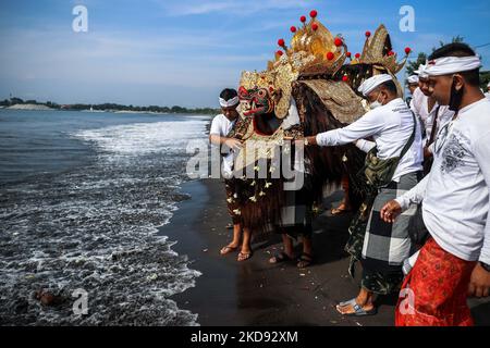 I devoti indù balinesi trasportano offerte durante il Melasti, una cerimonia di purificazione davanti a Nyepi alla spiaggia di Padang Galak a Denpasar, Bali, Indonesia 28 febbraio 2022. Il rituale Melasti si svolge ogni anno in vista del Nyepi Day of Silence, una cerimonia destinata a purificare e purificare le anime dei partecipanti indù balinesi. Nyepi è una celebrazione indù osservata ogni nuovo anno secondo il calendario balinese. La festa nazionale è uno di auto-riflessione e meditazione e attività come il lavoro, guardare la televisione, o viaggiare è limitato tra le ore 6:6 e le ore 14:00 (P Foto Stock