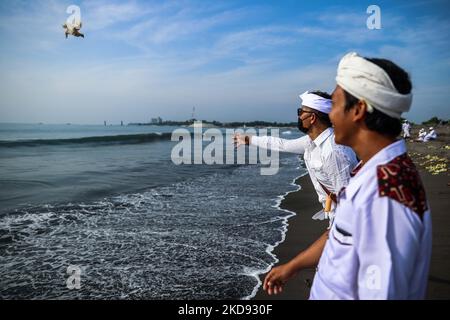 Un devoto indù balinese getta anatre nel mare come offerte agli dei durante il Melasti, una cerimonia di purificazione davanti a Nyepi alla spiaggia di Padang Galak a Denpasar, Bali, Indonesia 28 febbraio 2022. Il rituale Melasti si svolge ogni anno in vista del Nyepi Day of Silence, una cerimonia destinata a purificare e purificare le anime dei partecipanti indù balinesi. Nyepi è una celebrazione indù osservata ogni nuovo anno secondo il calendario balinese. La festa nazionale è uno di auto-riflessione e meditazione e le attività come il lavoro, guardare la televisione, o viaggiare è limitato tra t Foto Stock