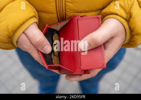 primo piano della mano di un uomo che tiene un portafoglio e che mostra le monete in euro in esso contenute. Foto Stock