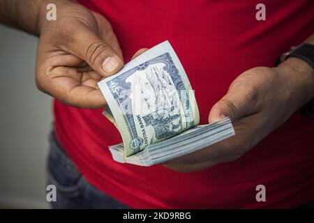 Primo piano ad una confezione di 50 rupie nepalesi mentre un uomo dietro il bancone conta la valuta cartacea. Ufficio del Centro di Cambio di moneta, un luogo per lo scambio di valuta estera con la rupia nepalese locale NPR nella zona di Thamel, a Kathmandu, la capitale del Nepal il 15 aprile 2022. Ci sono tavole che hanno tutti i prezzi scritti in base alla tariffa giornaliera. Thamel ha dozzine di uffici che offrono servizi di scambio in quanto è una popolare destinazione turistica. Lo scambio può essere offerto in banche, rivenditori autorizzati forex, hotel e l'aeroporto internazionale di Tribhuvan. La richiesta più comune di cambio è Euro, Dol US Foto Stock