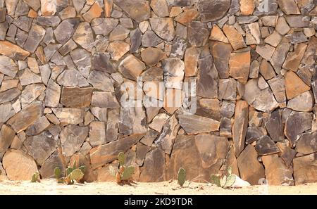 Una pietra grigia gialla fatta di lastre di pietra e arenaria sfondo, pietra sconnessa muratura texture, struttura rocciosa sfondo Foto Stock