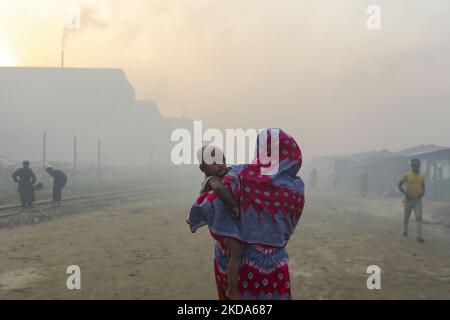 Le donne e i bambini sono vulnerabili condizionano un'area inquinata dall'aria mentre il fumo sale da un mulino di laminazione a Dhaka, Bangladesh, 16 maggio 2022. (Foto di Kazi Salahuddin Razu/NurPhoto) Foto Stock