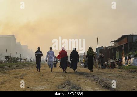 Le donne e i bambini sono vulnerabili condizionano un'area inquinata dall'aria mentre il fumo sale da un mulino di laminazione a Dhaka, Bangladesh, 16 maggio 2022. (Foto di Kazi Salahuddin Razu/NurPhoto) Foto Stock