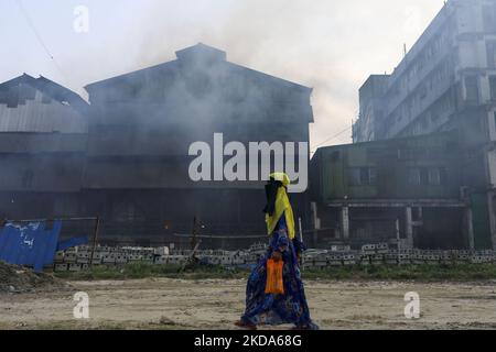 Le donne e i bambini sono vulnerabili condizionano un'area inquinata dall'aria mentre il fumo sale da un mulino di laminazione a Dhaka, Bangladesh, 16 maggio 2022. (Foto di Kazi Salahuddin Razu/NurPhoto) Foto Stock