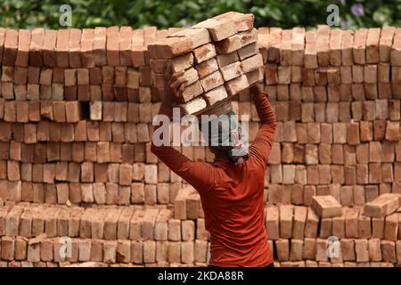 Un lavoratore scarica mattoni da una nave da carico nella zona di Kamrangirchar a Dhaka, Bangladesh il 18 maggio 2022. (Foto di Syed Mahamudur Rahman/NurPhoto) Foto Stock