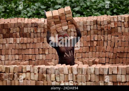 Un lavoratore scarica mattoni da una nave da carico nella zona di Kamrangirchar a Dhaka, Bangladesh il 18 maggio 2022. (Foto di Syed Mahamudur Rahman/NurPhoto) Foto Stock