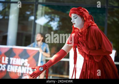 Un manifestante vestito di rosso per simboleggiare l'urgenza di agire contro le immissioni di gas riscaldanti si trova davanti a una bandiera che recita: "Non abbiamo tempo, quale futuro per i nostri figli?" LA XR France (Extinction Rebellion) e la ANV-COP21 hanno organizzato un "die-in" per protestare contro un vertice organizzato dalla TSE (Toulouse School of Economics) chiamato "Common Goods Summit" con il CEO di ExxonMobil Europe, il CEO di AXA France tra gli altri. Il tema è l'energia 'verde' (idrogeno, gas naturale) e la mitigazione dei cambiamenti climatici. XR e ANV-COP21 denunciano la presenza di ExxonMobil (che possiede diversi 'Clim Foto Stock