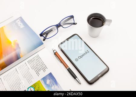 In questa foto, il 25 maggio 2022, un logo OpenAI visualizzato sullo schermo di uno smartphone su una scrivania accanto a un bar, una penna, occhiali e una rivista ad Atene, in Grecia. (Foto di Nikolas Kokovlis/NurPhoto) Foto Stock