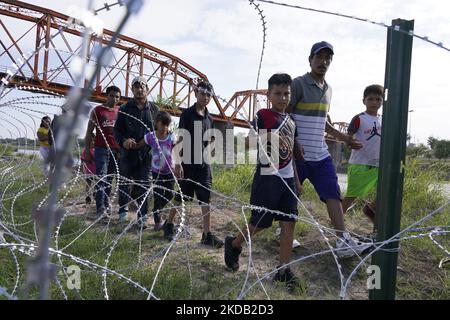 I migranti, la maggior parte con i bambini, seguono un percorso lungo il filo della concertina dove ultimatley saranno posti sotto la guardia di frontiera dopo aver attraversato il Rio Grande il 27 2022 maggio a Eagle Pass Texas, USA. Il titolo 42, il mandato dell’era Trump che era stato stabilito per impedire ai migranti di entrare negli Stati Uniti, Doveva scadere il 23 maggio, ma è stato bloccato da una causa intentata da diversi stati che citavano che la mossa di abbattere la legge “non è riuscita a soddisfare gli standard stabiliti dal Administrative procedure Act” e che non esiste una soluzione permanente per gestire l’inevitabile aumento dell’immigrazione. Oppositori al sostegno di Foto Stock